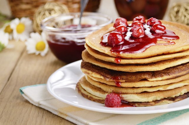 Delicious pancakes with raspberries on the wooden kitchen table