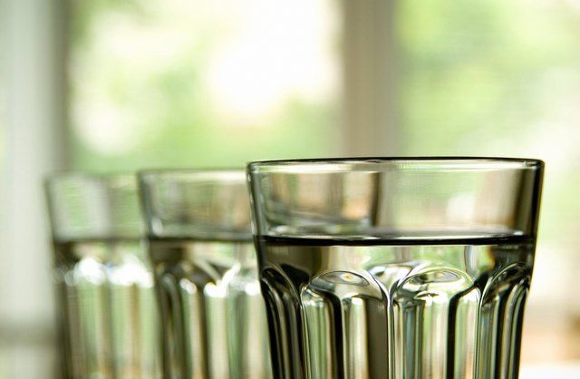 Three full clear glasses lined up with drinking water.
