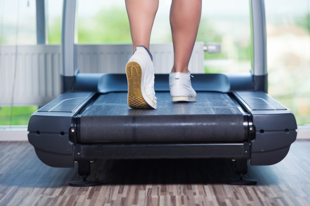 Fitness girl running on treadmill. Woman with muscular legs in