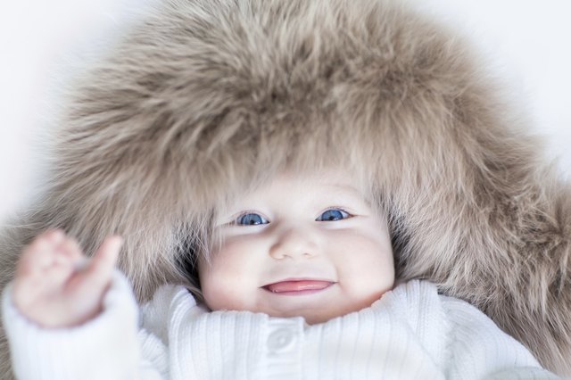 Funny baby girl with blue eyes wearing huge winter hat