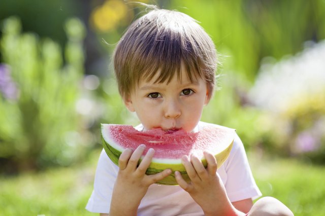 Boy, eating watermelon in the garden, summertime