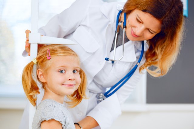 Doctor measuring height of a cute redhead girl.