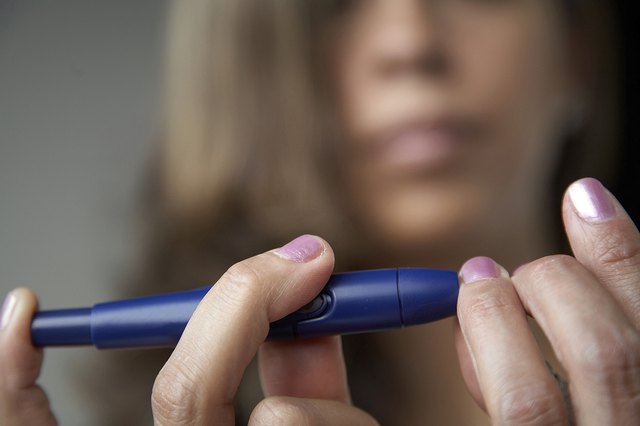 Close-up of a young woman taking a blood sample from her finger with a glaucometer