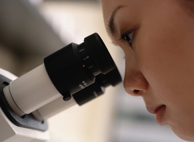 Young woman using microscope, close-up, side view