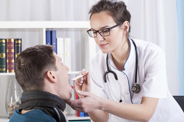 Doctor examining patient with sore throat
