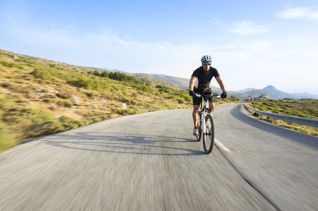 Cyclist man riding mountain bike in sunny day .