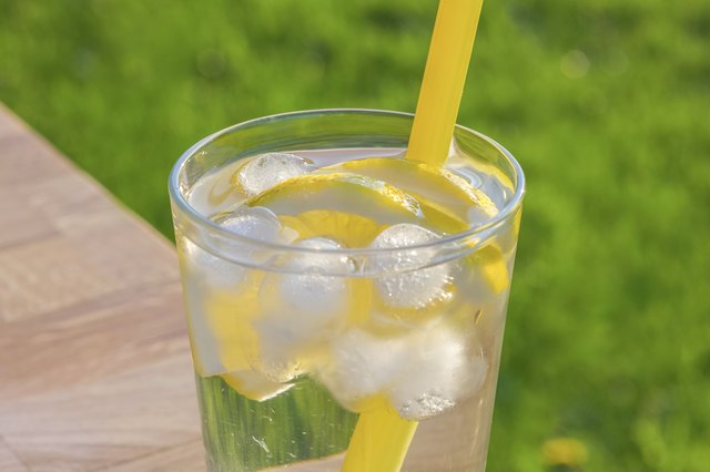 Glass of ice water with lemon slices and straw