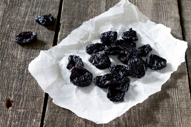Dried plums on a dark background in a rustic style.