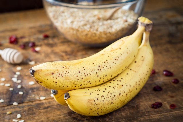Bananas and oats on wooden table, close up