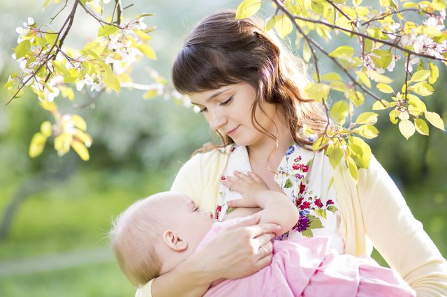 young mother breast feeding her baby girl at sunny day