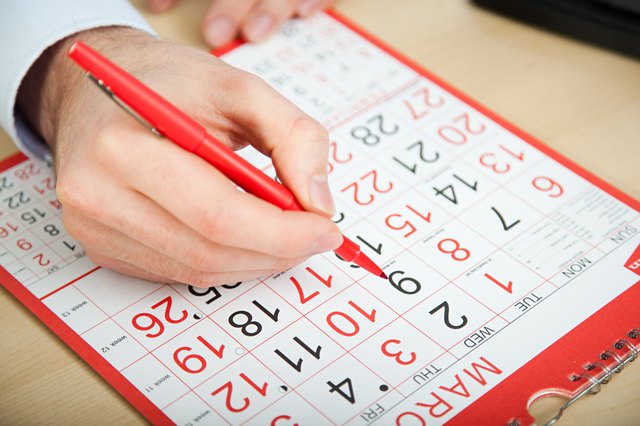 Office worker marking calendar with red pen