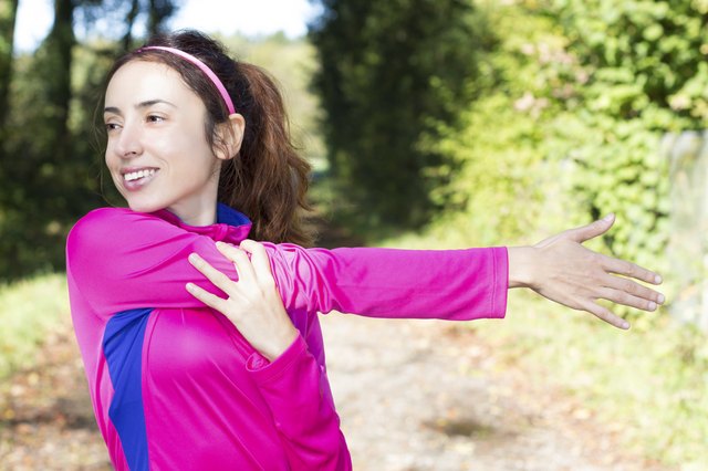 Sporty woman stretching her arm in forest