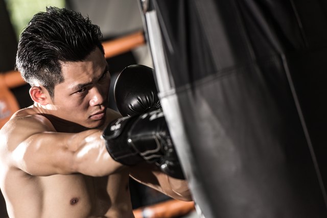 young muscular fighter training on a punching bag