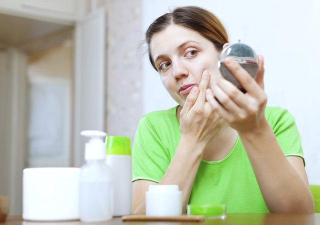 girl stares on face in mirror