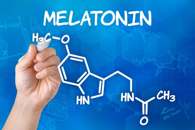 Hand with pen drawing the chemical formula of melatonin