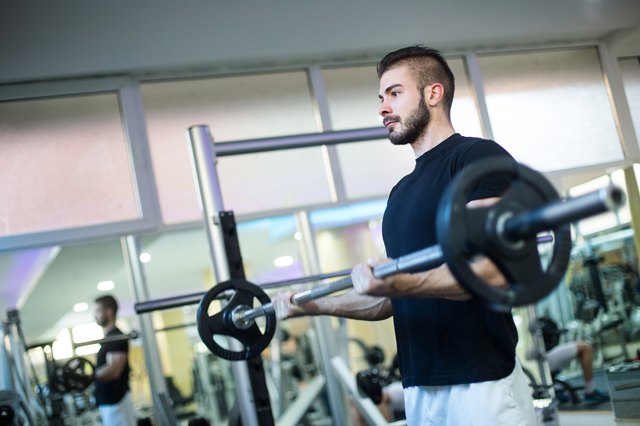 Muscular Bodybuilder Men Doing Exercises with Dumbbells in Gym