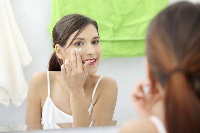 Woman applying moisturizer cream on face