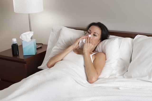 Sick Woman in Bed Blowing Nose