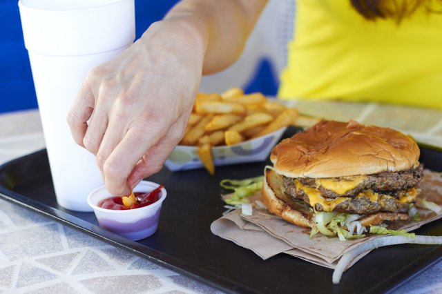Female Hand Dipping Fries In Tomato Sauce