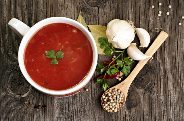 Tomato soup and spices on wooden table