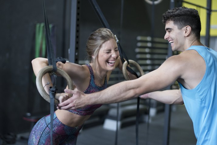 Man helps laughing woman with ring training with complicity