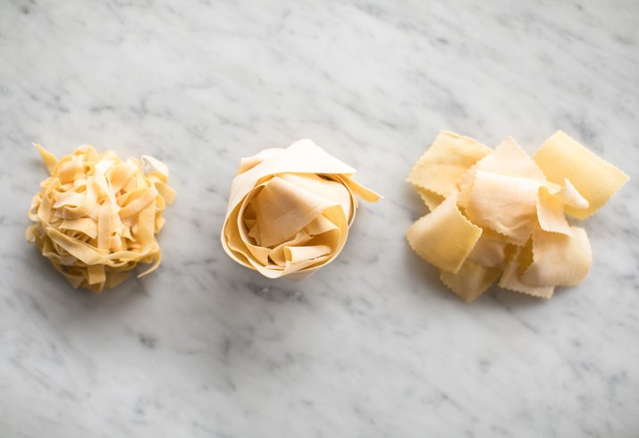 Different pasta shapes on marble background