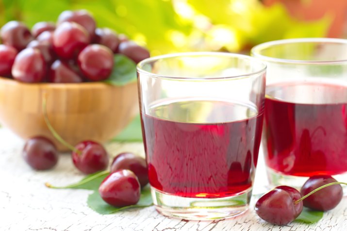 cherries and a glass of cherry juice on a wooden table