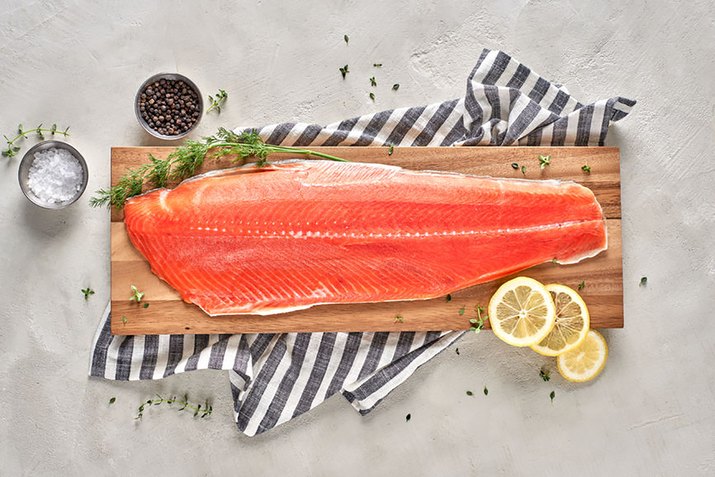 salmon filet with salt and lemon on cutting board