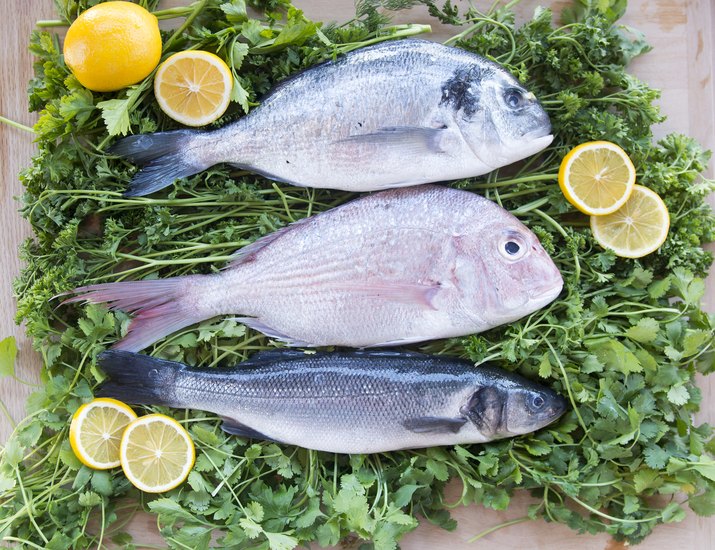 Raw fish on a bed of greens with lemons