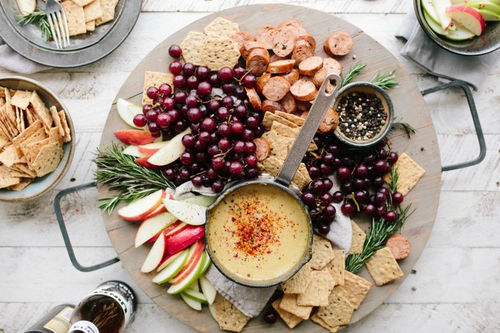 Cheese board filled with fruit, crackers and grapes