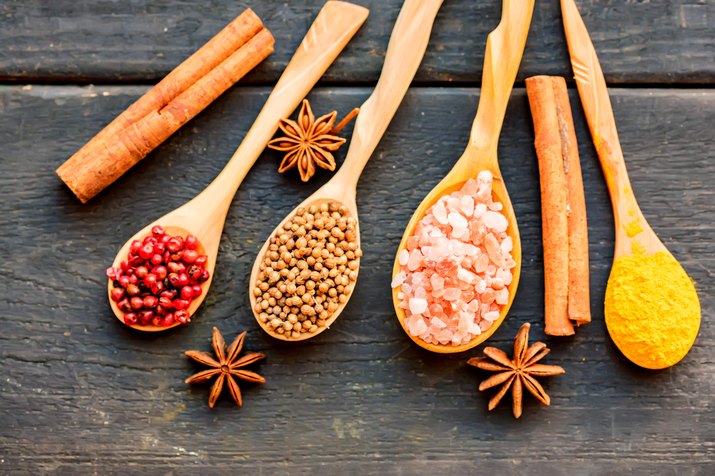 Various colorful herbs and spices in wooden spoons