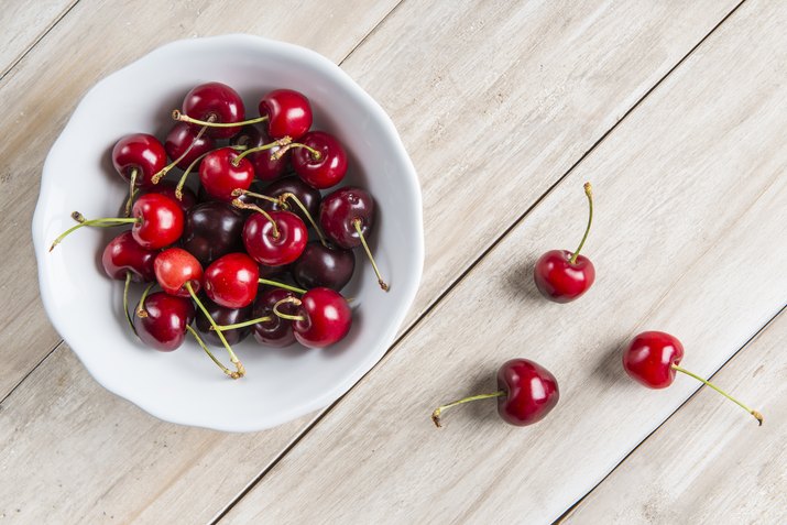 White bowl of cherries on the table