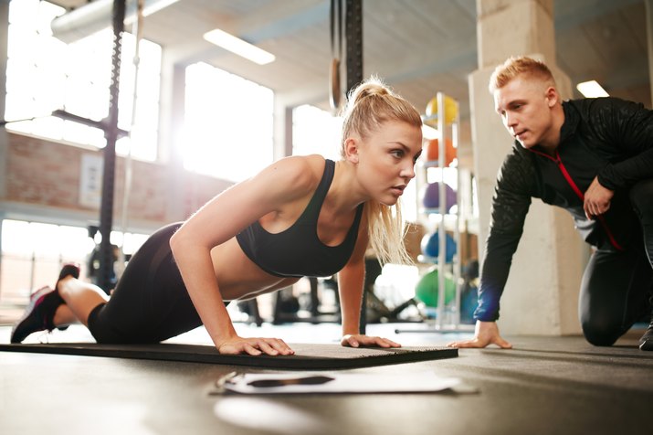 Trainer helping woman do push-ups