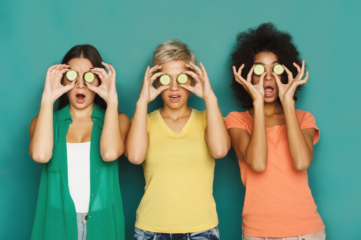 Three beautiful girls covering eyes with cucumber pieces