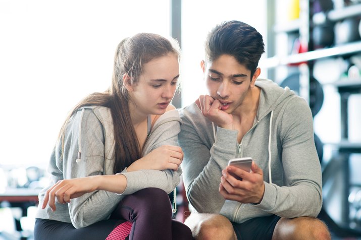 Fit couple in modern gym with smartphone