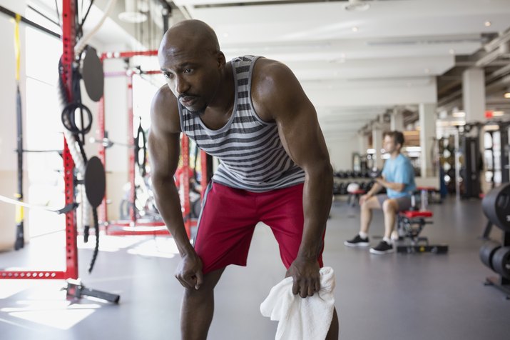 Tired man resting with hands on knees at gym