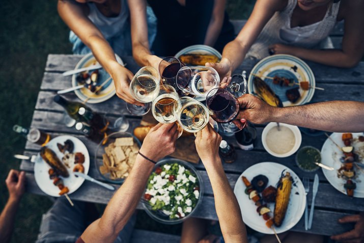 Friends at outdoor cookout toasting with wine glasses