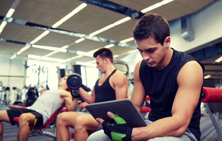 group of men with tablet pc and dumbbells in gym