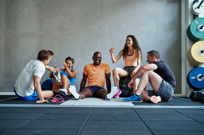 Diverse group of friends sitting together in a gym laughing