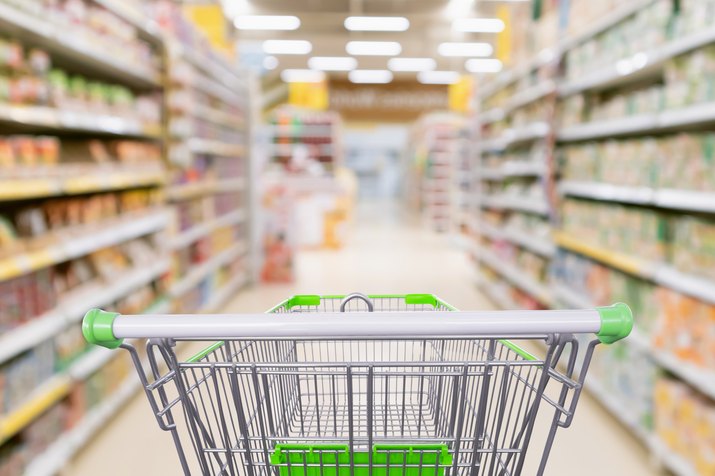 Empty shopping cart with abstract blur supermarket discount store aisle and product shelves interior defocused background