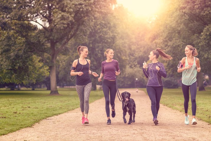 Healthy women jogging at the park with a dog
