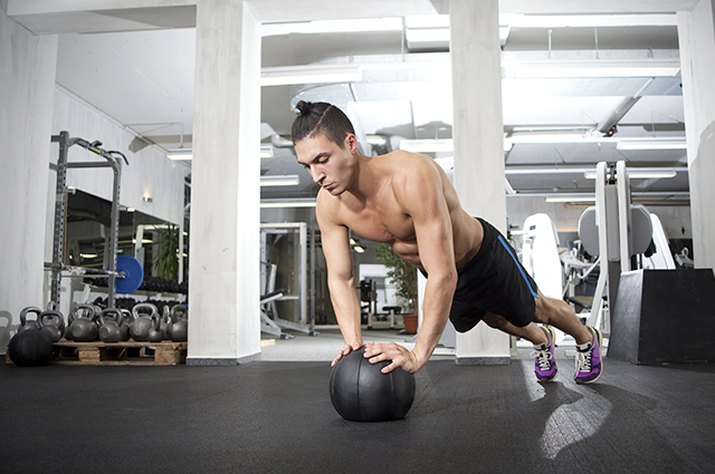 Man doing CrossFit workout on a medicine ball in a gym