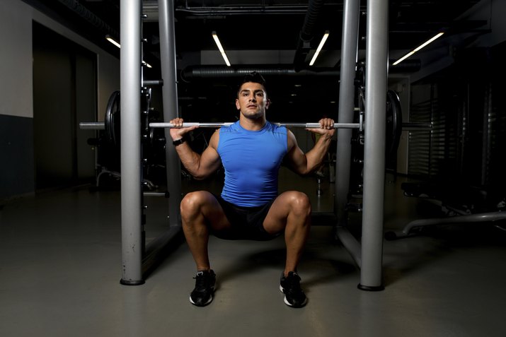 Young man exercising with barbell Squats