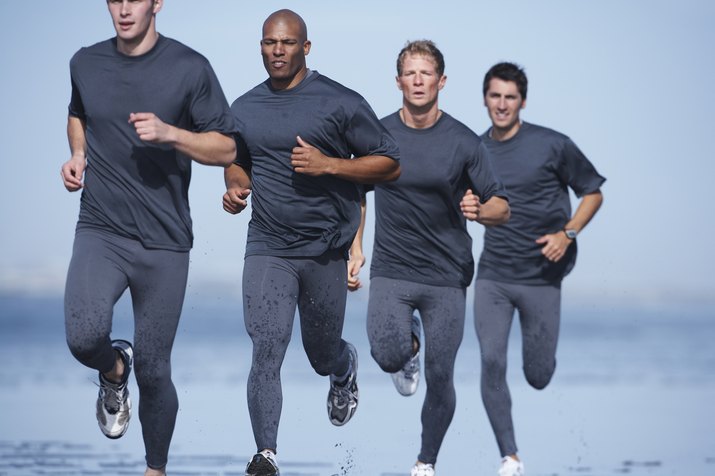 Four men jogging on beach