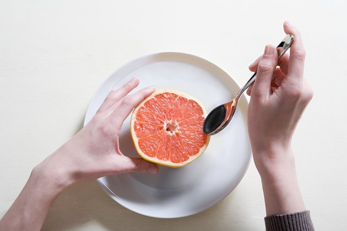 Young woman eating grapefruit