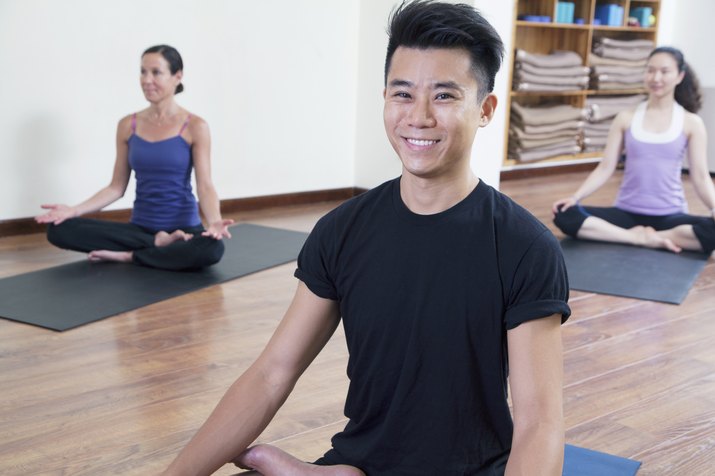 Smiling man sitting cross-legged in a yoga class