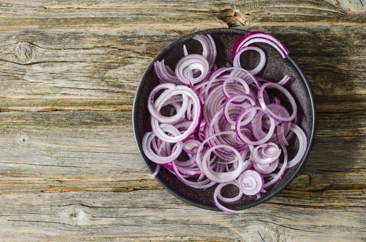 Bowl of sliced red onions on wood