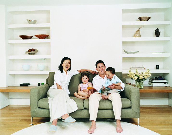 Smiling Family of Four Sitting on a Sofa in a Living Room