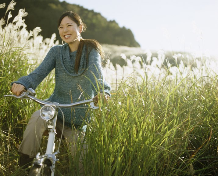 Woman Emerging from Long Grass on a Bicycle