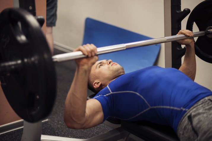 Focused man doing workout on weight bench